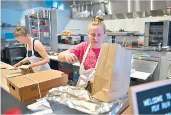  ?? Hyoung Chang, The Denver Post ?? Kelsie Bernes, left, and Lauren Brendel packing food for customer pickup.