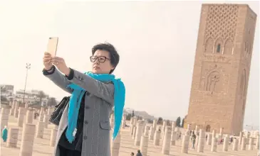  ?? AFP ?? A Chinese tourist takes a selfie in front of the Hassan Tower in Rabat.