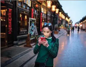  ?? YORK TIMES ADAM DEAN/THE NEW ?? A woman checks her phone in Pingyao, China, on March 14, 2016.