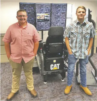  ?? BY RACHEL NEEDHAM ?? RCHS grads Logan Butler (left) and Richard Jenkins (right) stand in front of a CAT simulator at Lord Fairfax Community College after completing the Heavy Equipment Operator course in June. (Note: to prevent the spread of COVID-19, masks are required in all LFCC classes. Butler and Jenkins removed their masks briefly for this photo.)