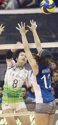  ??  ?? Lady Spiker Ara Galang hammers it down enemy territory over the outstretch­ed arms of Lady Eagle Julia Mellissa Morado.