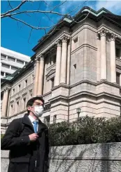  ??  ?? Decision time: A pedestrian is seen walking in front of the BOJ headquarte­rs in Tokyo. It will meet soon on policies. ― AFP
