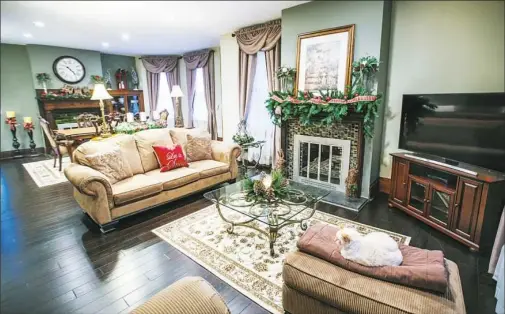  ?? Andrew Rush/Post-Gazette photos ?? The living room of Cindy and Bruce Berringer’s home in Crafton and, below, the porch festooned with Christmas decoration­s. A door with leaded glass has a period knob perfect for hanging bells and greenery.