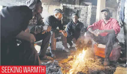  ?? Picture: Neil McCartney ?? A group of residents sit in a derelict building in Alexandra that used to contain their homes. A fire destroyed the building, which housed a large number of shacks, at the weekend.