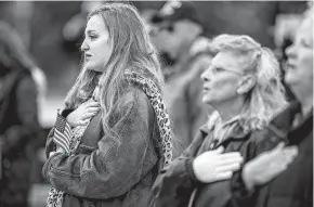  ?? Josie Norris / Staff photograph­er ?? People attending the Veterans Day ceremony at Fort Sam Houston National Cemetery place their hands over their hearts during the national anthem. This year’s observance of Veterans Day also marks a century since the end of World War I.