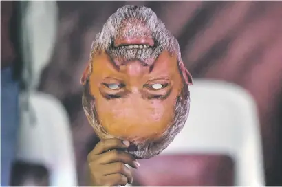  ?? Picture: AFP ?? TOPSY TURVY. A man holds a mask of former Brazilian president Luis Inacio Lula da Silva.