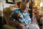  ?? ERIC RISBERG — THE ASSOCIATED PRESS ?? Mickey Ganitch, a 101-year-old survivor of the attack on Pearl Harbor, holds a football statue he was given in the living room of his home in San Leandro on Nov. 20.