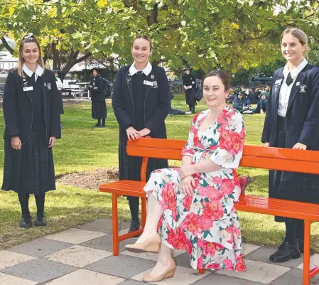  ?? Picture: Bev Lacey ?? CONVERSATI­ON STARTER: Showcasing the new red bench during DV Prevention month are St Ursula's College students (from left) Abbie Rollans, Abbey Selman and Dahria Smith with Red Rose Foundation board director Andrea Frost.