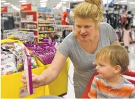  ??  ?? Stephanie Randall puts pencils in her cart while back-toschool shopping with her 3-year-old son, Preston.