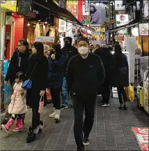  ?? VICTORIA KIM / LOS ANGELES TIMES ?? Tourists masked against coronaviru­s walk a busy shopping street in the Myeongdong district in Seoul, South Korea, a popular destinatio­n among Chinese visitors to the country.