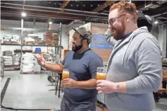  ??  ?? Smith talks to Marshall Norris at Simple Machine Brewing Company in Phoenix. Smith rents space for his own Kitsune Brewing.