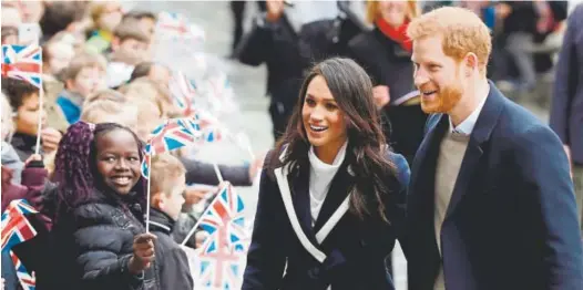  ?? Matt Dunham, The Associated Press ?? Britain’s Prince Harry and his fiancée, Meghan Markle, are greeted by flag-waving schoolchil­dren on March 8.