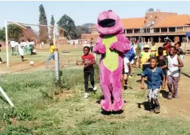  ??  ?? Children have fun with the mascot (Barney) during the Collen Nyambiya soccer tournament and Young Flying Stars Soccer Academy (YFSSA) 7th Anniversar­y celebratio­ns held at Raylton Sports Club in Bulawayo on Saturday. — (Picture by Nkosizile Ndlovu)