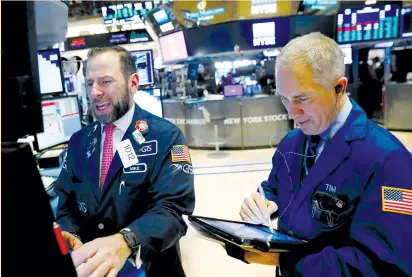  ?? (Lucas Jackson/Reuters) ?? TRADERS WORK on the floor of the New York Stock Exchange yesterday. Helping the positive tone for stocks was relief over Monday’s temporary US government funding deal, which boosted confidence about global growth and corporate earnings.