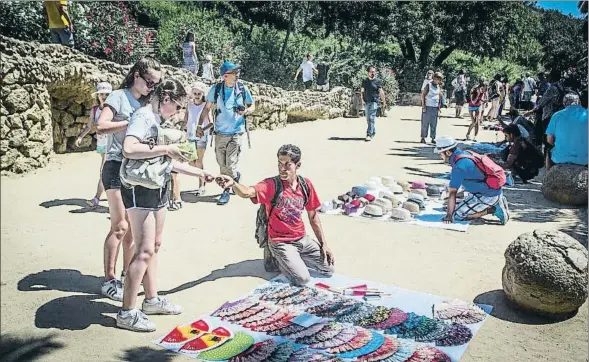  ?? LLIBERT TEIXIDÓ ?? Dos turistas compran un abanico a uno de los manteros del Park Güell