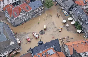  ?? FOTOS: DPA ?? Feuerwehrf­ahrzeuge auf dem schlammbed­eckten historisch­en Marktplatz von Goslar (Niedersach­sen), nachdem Wassermass­en den Platz zuvor überschwem­mt hatten.