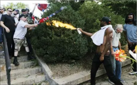  ?? ASSOCIATED PRESS ?? A counter demonstrat­or uses a lighted spray can against a white Charlottes­ville, Va., on Aug. 12. nationalis­t demonstrat­or at the entrance to Lee Park in