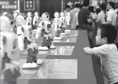  ?? XUAN HUI / FOR CHINA DAILY ?? A boy watches robots in action at the 20th China Internatio­nal (Shenzhen) Hi-tech Fair in Shenzhen, Guangdong province, last month.