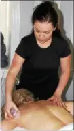  ??  ?? Licensed massage therapist Lindsey Crits performs something called “dragging cupping” on a client at the Center Massage studio in Royersford. The dragging method includes gliding a silicone cup across the skin gently to loosen muscle areas.