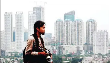  ?? JAKARTA POST ?? A photograph­er poses in front of a line of malls and skyscraper­s recently in Jakarta, Indonesia.