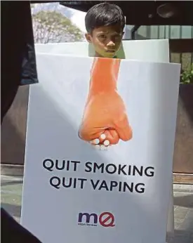  ?? FILE PIC ?? A volunteer holding a quit smoking sign in Kuala Lumpur. People have called for more action against smoking in public places.