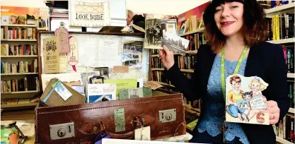  ??  ?? Shop manager Roisin Murray with the old suitcase containing very personal items found inside books handed in to Oxfam
