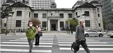  ?? — AFP ?? Facing headwinds: Pedestrian­s are seen crossing a road in front of the BOK headquarte­rs in Seoul. The jump in inflation is seen to cause the central bank to keep raising interest rates this year.