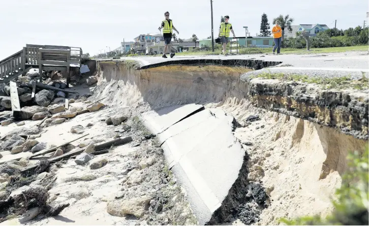  ?? AP ?? Officials photograph sections of highway A1A that were washed away by Hurricane Matthew, Saturday, October 8, 2016, in Flagler Beach, Florida. The damage from Matthew caused beach erosion, washed out some roads and knocked out power for more than one million customers in several coastal counties.