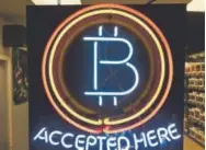  ?? Gillian Flaccus, The Associated Press ?? A neon sign hanging in the window of Healthy Harvest Indoor Gardening in Hillsboro, Ore., shows that the business accepts bitcoin as payment.