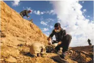  ?? Safin Hamed / AFP / Getty Images 2015 ?? A man inspects the remains of a Yazidi victim in 2015 killed by Islamic State fighters in Sinjar, Iraq.