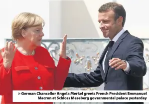  ??  ?? > German Chancellor Angela Merkel greets French President Emmanuel Macron at Schloss Meseberg government­al palace yesterday