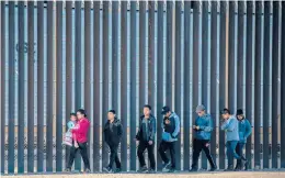  ?? JOHN MOORE/GETTY ?? Immigrants walk Thursday along the border wall that separates El Paso, Texas, from Ciudad Juarez, Mexico. More than 100,000 migrants attempted to cross the border into the U.S. last month — the most since March 2019 under former President Trump.