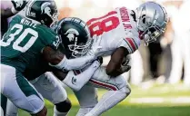  ?? CARLOS OSORIO / ASSOCIATED PRESS ?? Ohio State wide receiver Marvin Harrison Jr. (18) pulls Michigan State cornerback Justin White (30) and cornerback Ameer Speed into the end zone for a touchdown during Saturday’s 49-20 Buckeyes victory.