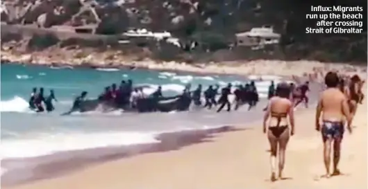  ??  ?? Influx: Migrants run up the beach after crossing Strait of Gibraltar