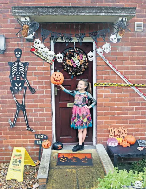  ??  ?? Talulah Hudson, eight, gets ready for trick or treating with a difference as she organises Hallowe’en decoration­s outside her home in Woodlesfor­d, Leeds.