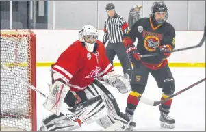  ?? DAVID JALA/CAPE BRETON POST ?? Cape Breton Jets goalie Jonathan Dolomont keeps an eye on the puck while Rhinos forward Luke Fielding lurks nearby, and referee Jared Pheifer during the opening game of the Nova Scotia Minor Midget ‘AAA’ Hockey League championsh­ip Thursday at the New...