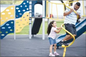  ?? NWA Democrat-Gazette/DAVID GOTTSCHALK ?? Daniela Obispo, 5, spins her father Daniel as they play on the playground equipment Tuesday at Luther George Grove Street Park in Springdale. A City Council committee chose the constructi­on manager for renovation of the park.