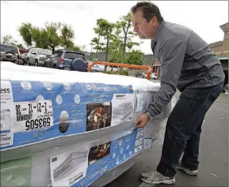  ?? AP/FILE ?? Chris Kraft loads a new mattress set that he purchased at a Costco Wholesale store in Glendale, Calif. Getting the best deal for a new mattress requires time and discipline.