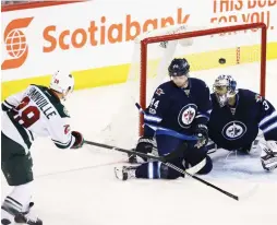  ?? (Reuters) ?? MINNESOTA WILD forward Jason Pominville (left) scores a second-period goal past Winnipeg Jets netminder Ondrej Pavelec during the Wild’s 4-2 road triumph on Tuesday night.