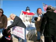  ?? WAYNE PARRY - THE ASSOCIATED PRESS ?? In this Nov. 10 photo, volunteers hold a “Save The Lighthouse” rally near the East Point Lighthouse in Maurice River Township, N.J. Rising seas and erosion are threatenin­g lighthouse­s around the U.S. and the world, including the East Point Lighthouse. With even a moderate-term fix likely to cost $3 million or more, New Jersey officials are considerin­g what to do to save the lighthouse.