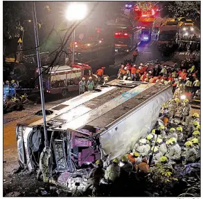  ?? AP/Apple Daily ?? Firefighte­rs work to remove injured passengers from a double-decker bus that crashed Saturday in a rural area of Hong Kong. As of Saturday night, at least 18 people had died and more than 60 had reported injuries. Passengers said the driver had been...