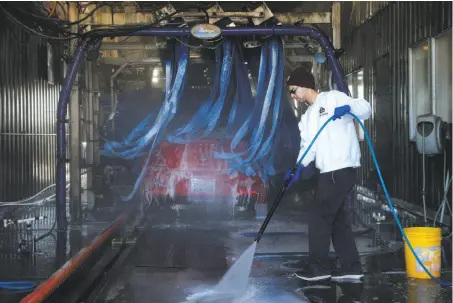 ?? Photos by Santiago Mejia / The Chronicle ?? Employee Cole Gomez hoses down the area after a vehicle is washed at the 5 Star Car Wash and Detail Center in Fairfield.