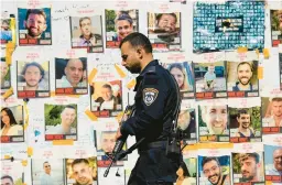  ?? ARIEL SCHALIT/AP ?? An Israeli policeman walks by hostage pictures Monday in Tel Aviv. Israeli negotiator­s have signaled that Israel may trade some high-profile Palestinia­ns for hostages.