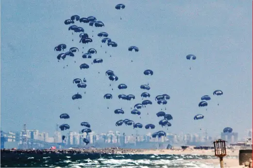  ?? AFP ?? Humanitari­an aid is dropped on the Gaza Strip, west of Gaza City, on Monday with the background showing Israel’s Rutenberg power station near Ashkelon. Seven people have drowned in the Mediterran­ean trying to reach aid airdropped into Gaza, the Hamas-run territory’s health ministry said on Tuesday. Six people were also injured in the previous day’s airdrop, the ministry said.—