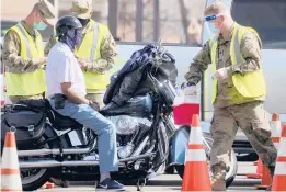  ?? MARIO TAMA/GETTY ?? A National Guard member prepares to inoculate a motorcycli­st Tuesday at a mass vaccinatio­n site in Los Angeles. The site is run with the assistance from FEMA. About 12% of the U.S. population has received at least one vaccine dose, the CDC said.