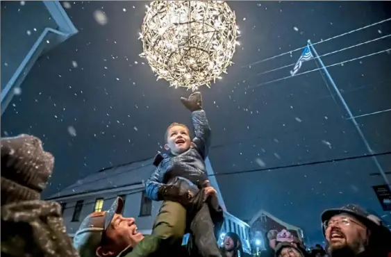  ?? Steph Chambers/Post-Gazette ?? Angelo Cammisa, 3, of Harmony, touches the ball after it dropped at 6 p.m. — midnight German time — while lifted by his father, Tim Cammisa, during a “Silvester” celebratio­n, reflecting Harmony’s historic German roots, on Tuesday. Harmony was founded in 1804 by German immigrants. In Germany, the celebratio­n of New Year’s Eve is commonly called Silvester, after fourth-century Pope Sylvester, who died on the last day of the year 335.