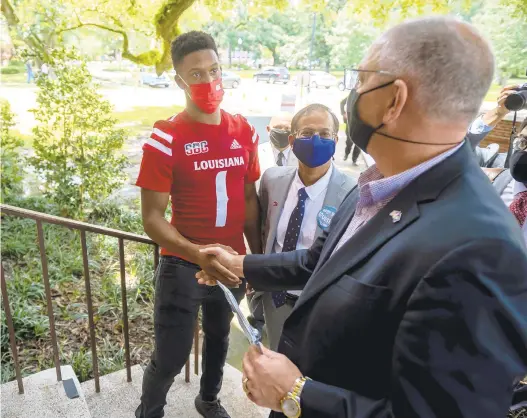  ?? SCOTT CLAUSE/THE DAILY ADVERTISER VIA AP ?? Louisiana quarterbac­k Levi Lewis greets Gov. John Bel Edwards as he tours the University of Louisiana campus COVID-19 vaccinatio­n site in August as part of the university’s Shot for $100 campaign.