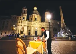  ?? AP PHOTO/ALESSANDRA TARANTINO ?? A waiter clears a table at a cafe in Piazza Navona Square before the start of a curfew on Oct. 23.