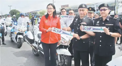  ??  ?? Mohd Sar’ie, flanked by Davina and Aidil, showing the ‘Ops Selamat’ sticker. — Photo by Chimon Upon