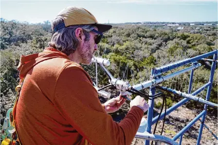  ?? Robin Jerstad/contributo­r ?? Tyson Mckinney, a science associate with the University of Texas at Austin, performs maintenanc­e work on a research station that lies near the Balcones Escarpment. An escarpment is a continuous line of cliffs or steep slopes facing in one general direction.